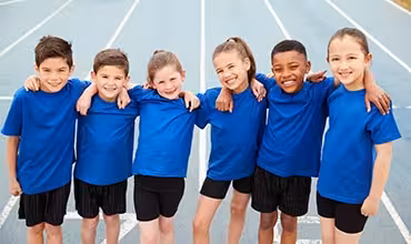 Niños con uniforme deportivo azul abrazados en una pista de atletismo