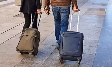 Viajeros caminando con maletas de ruedas